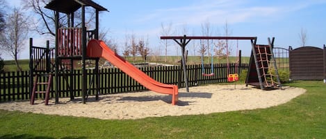 Un parque infantil con tobogán, columpios y estructuras para escalar.