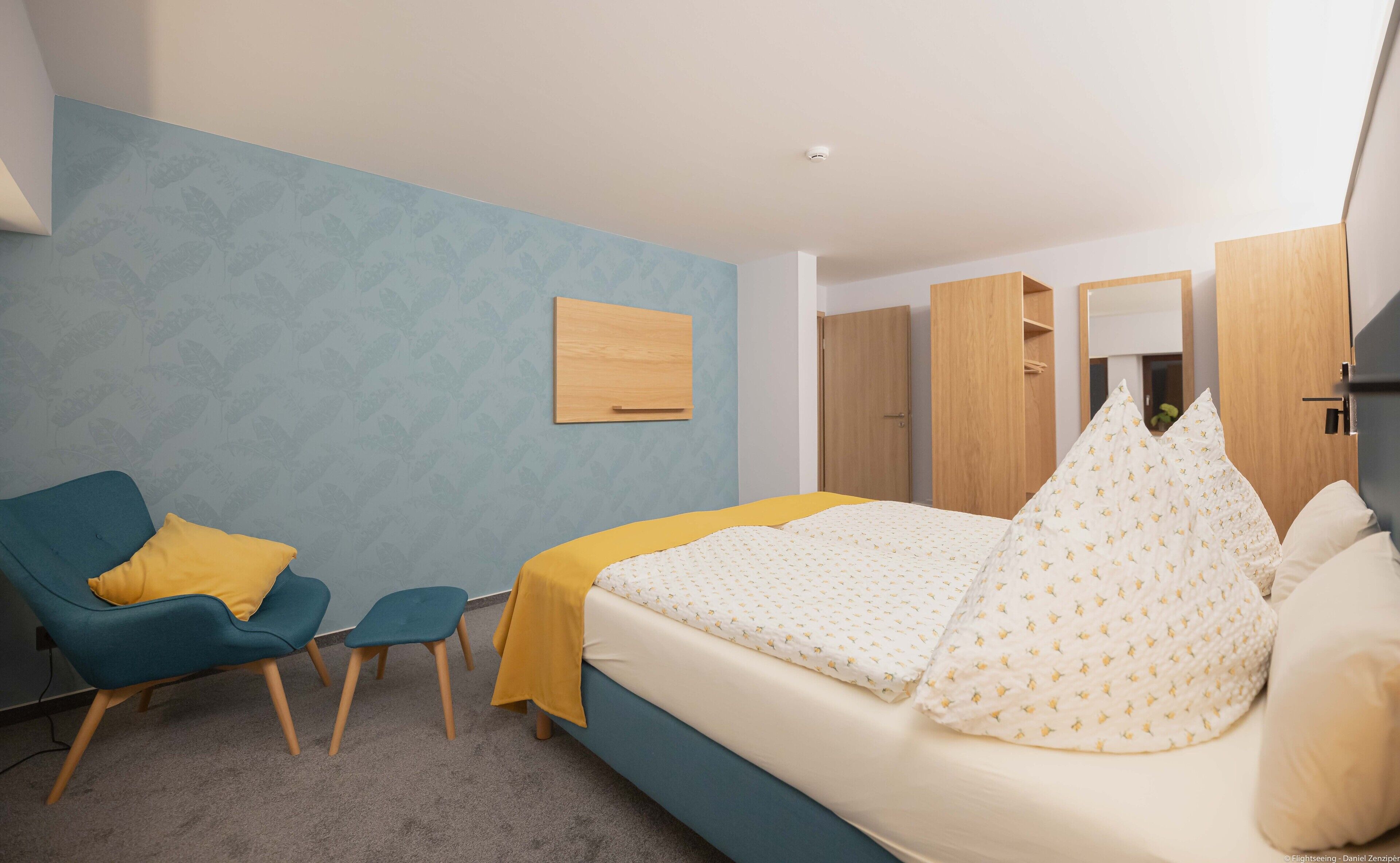 Una camera da letto con un letto, una sedia, un tavolino e un armadio.