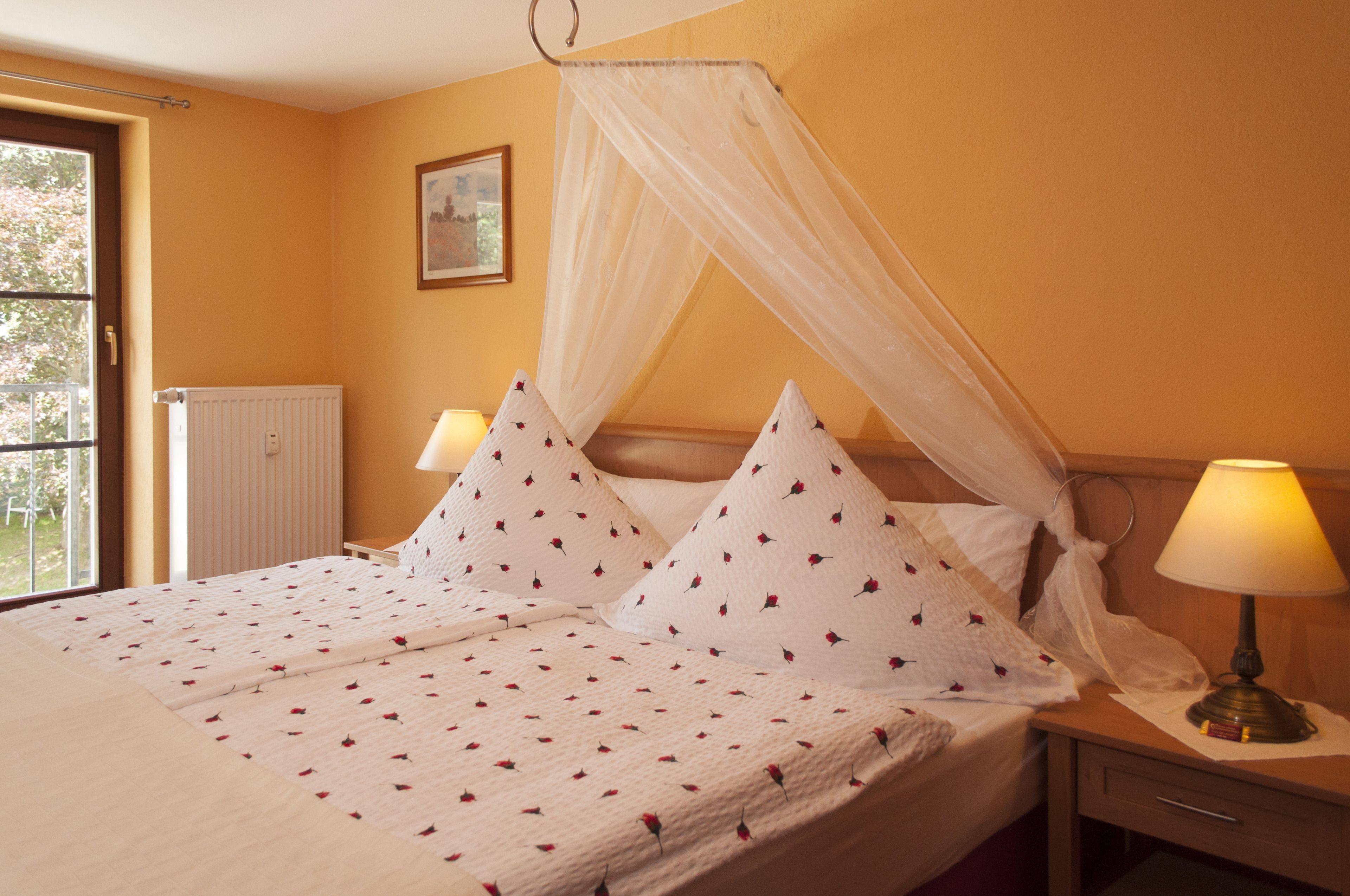 A bed with a canopy, two bedside lamps, and a radiator.