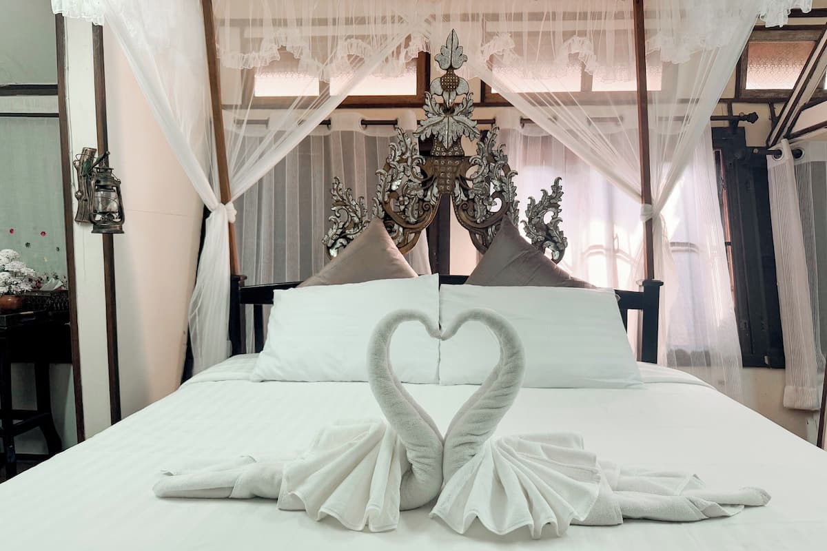 A bed with white linens, a canopy, and a decorative headboard.