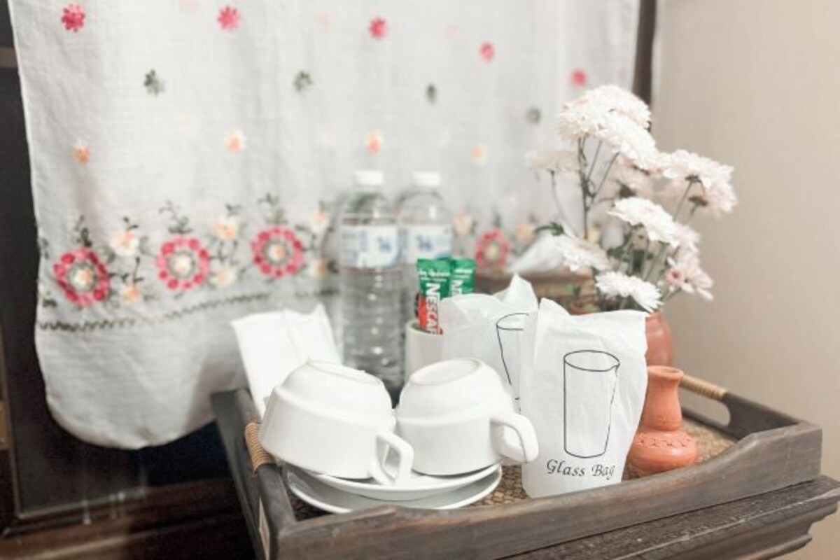 Un plateau avec des tasses blanches, un verre et un vase rempli de fleurs.