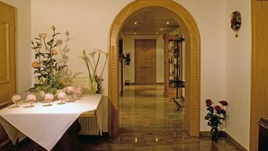 A hallway with a white table set with pink roses and a vase of flowers. - Hotel zum Fischerwirt (Ried)