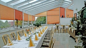 A long dining table set for a formal event with chairs and a glass ceiling above. - Hotel zum Fischerwirt (Ried)