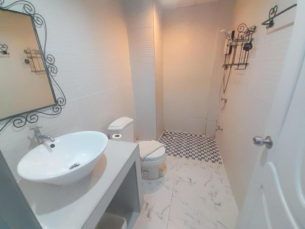 Un baño pequeño con un lavamanos, inodoro y ducha blancos.