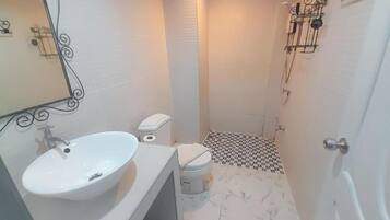 A small bathroom with a white sink, toilet, and shower.