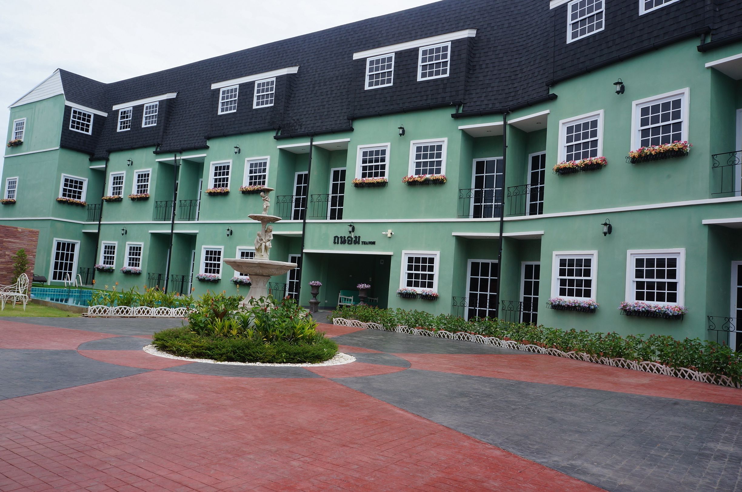 Un edificio verde con numerosas ventanas y una fuente en el centro.
