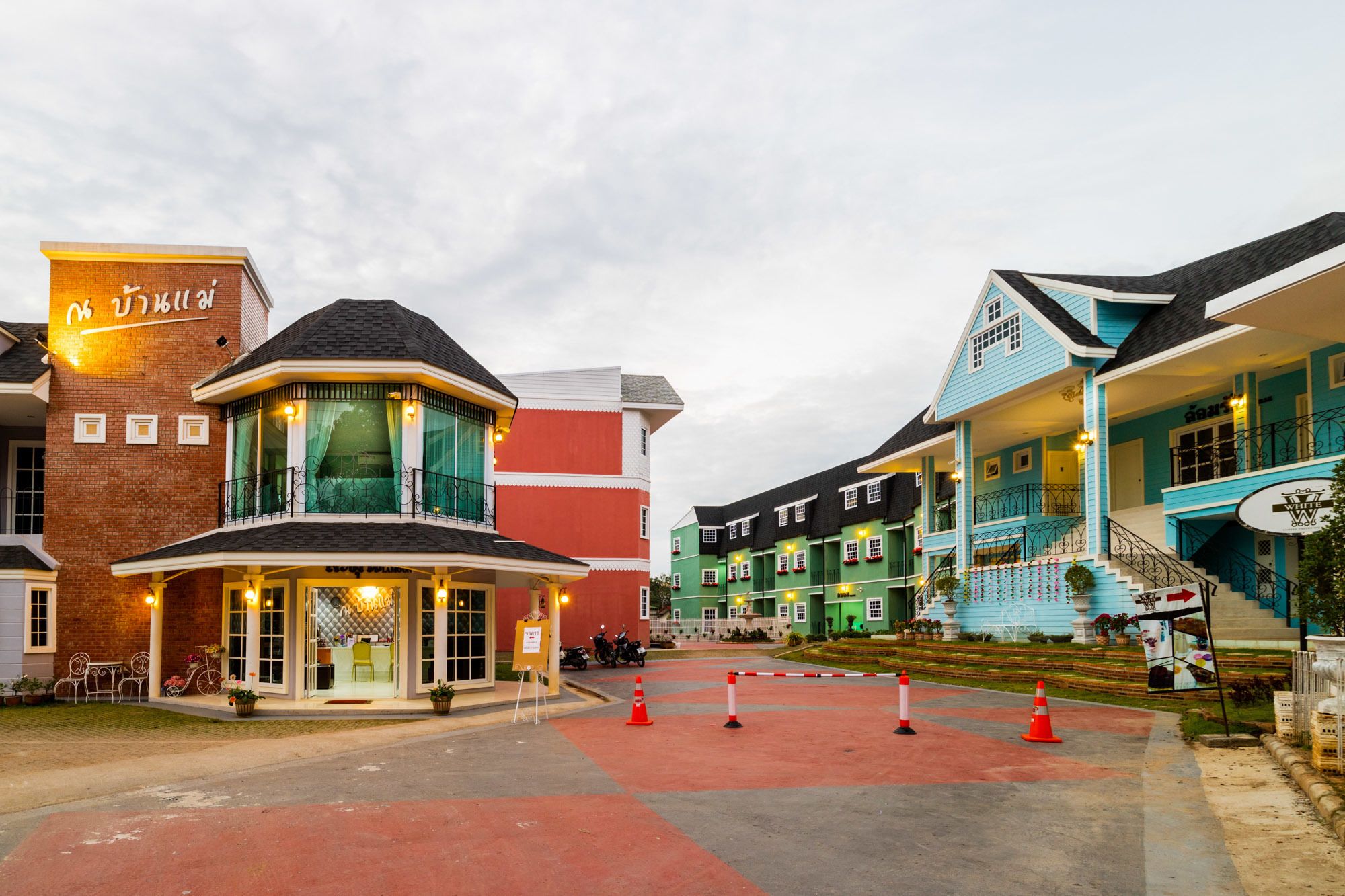 A row of colorful buildings with a central entrance area, including a restaurant and a bar.