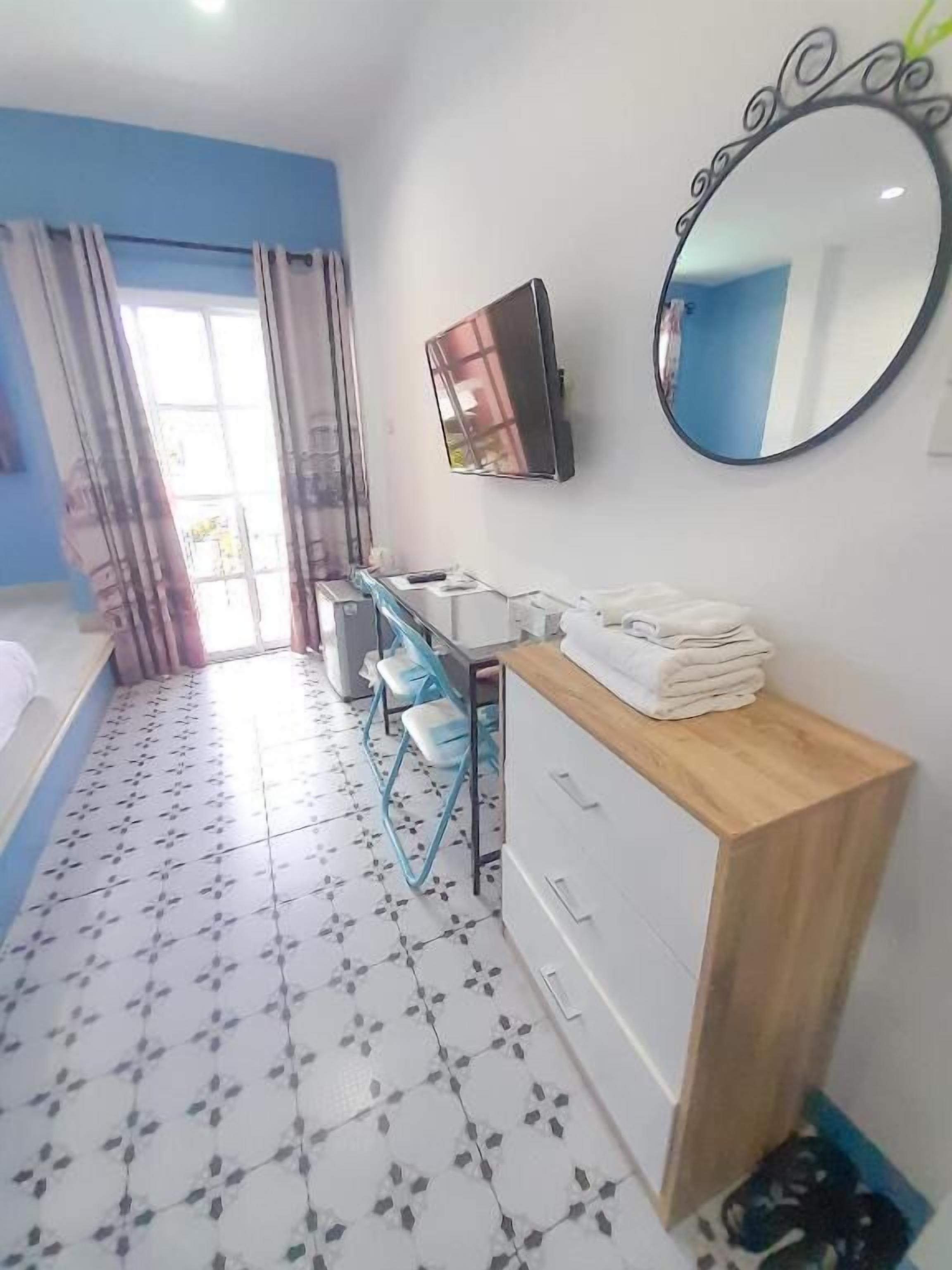 A bathroom with a wooden vanity, a mirror, and a tiled floor.