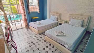 Habitación de hotel con dos camas, una mesita y vistas al exterior.