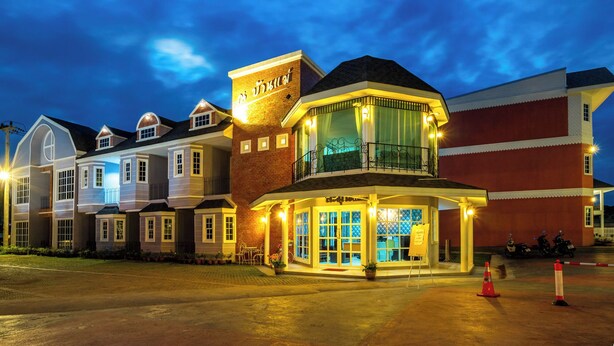 A hotel with a prominent entrance, a balcony with a railing, and a sign above the entrance.