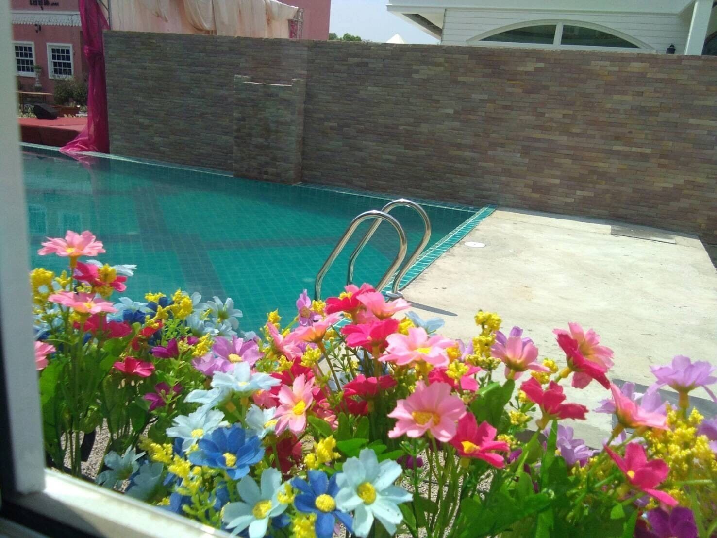 Una piscina con pared de piedra y solárium de hormigón.
