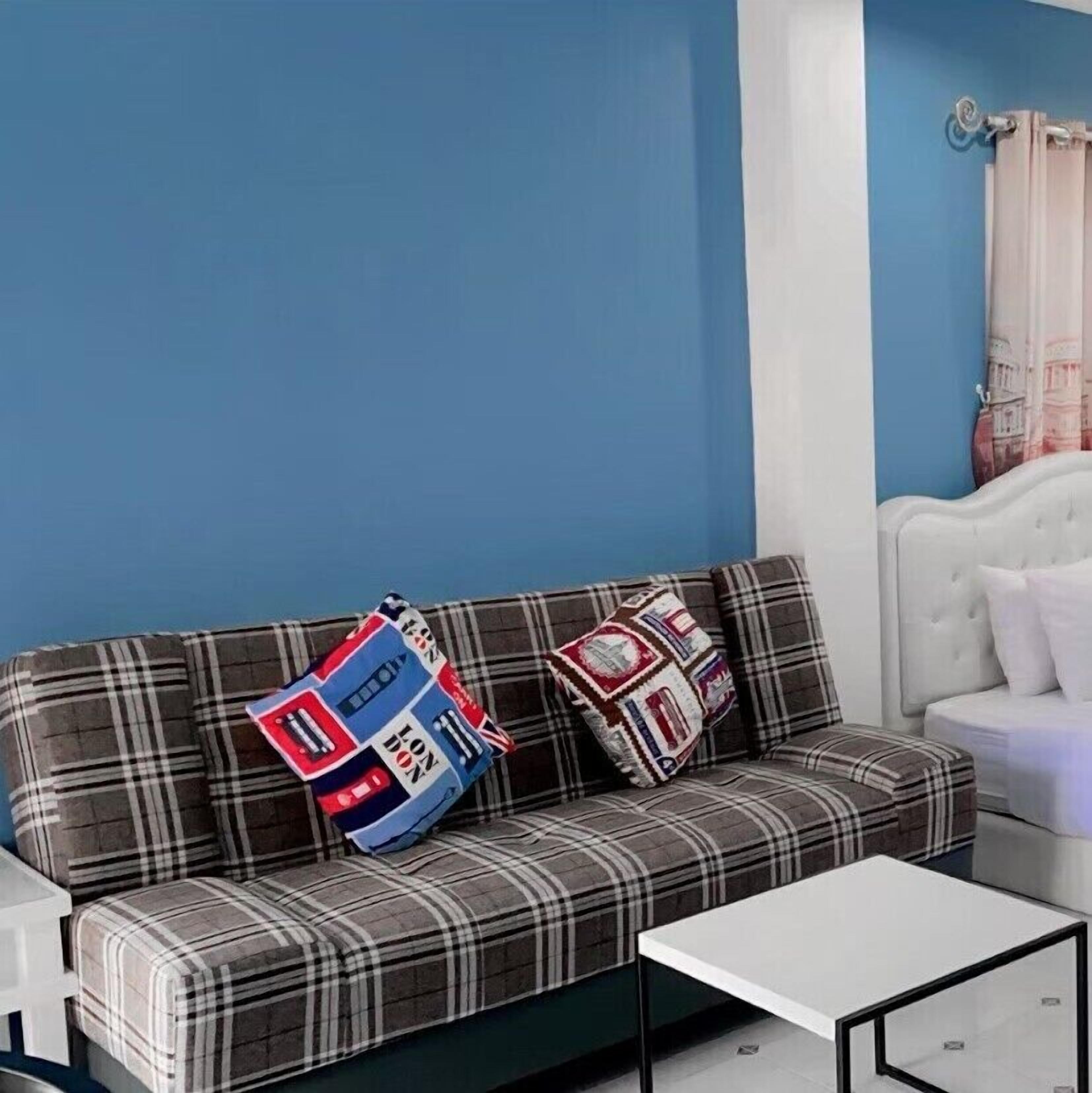 A room with a plaid sofa, a white coffee table, and a blue wall.