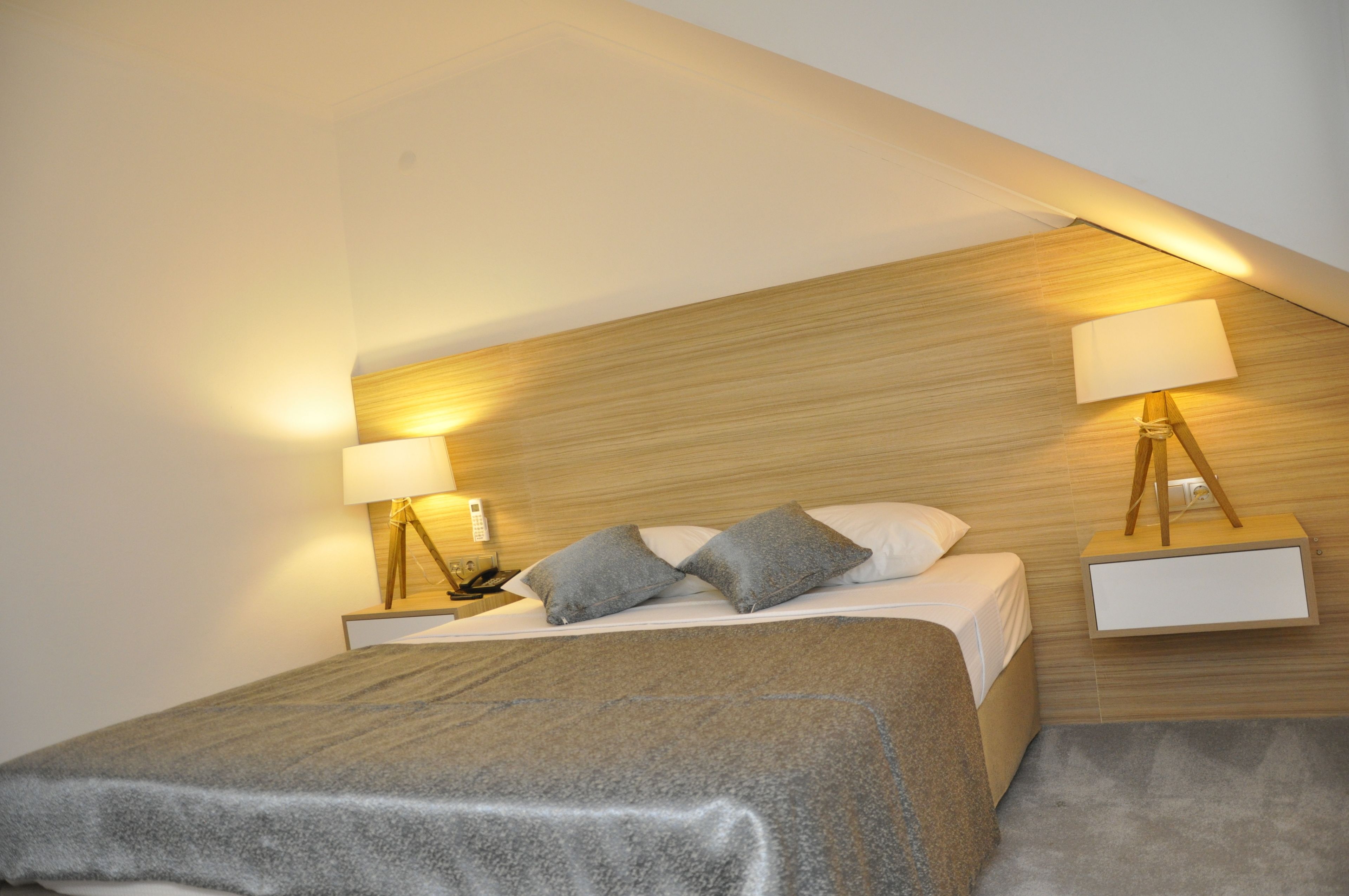 A bedroom with a bed, two bedside tables, and two wall-mounted lamps.