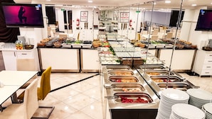 A buffet setup with multiple food stations and a seating area with tables and chairs. - Ozyigit Otel (Gazipasa)