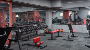 Una palestra con diverse attrezzature per esercizi, tra cui manubri, kettlebell e panche.