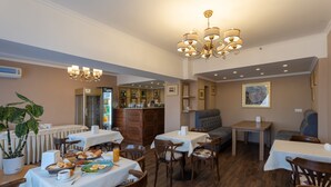 Zona pranzo con tavoli, sedie, un lampadario e un frigorifero.