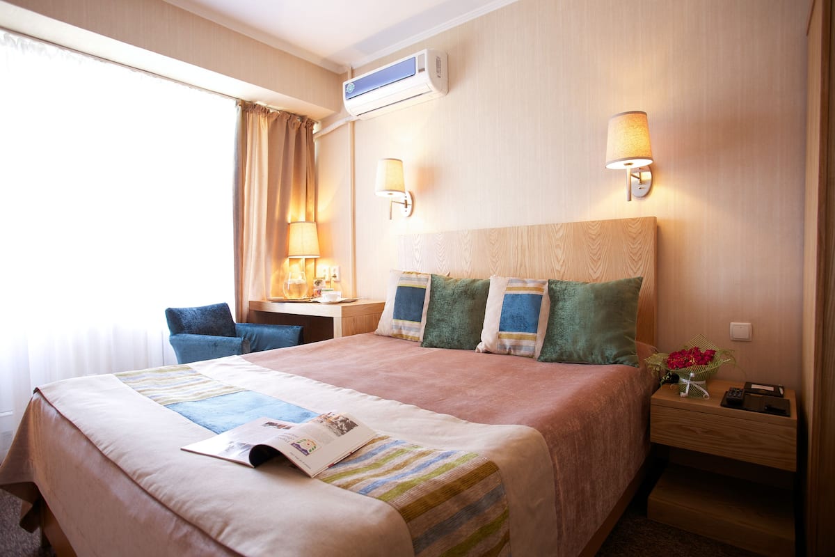 Una habitación de hotel con cama, lámparas de noche, escritorio y una silla.