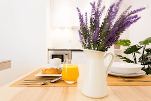 A breakfast setting with a croissant, orange juice, and a pitcher of juice on a wooden table. - Apartamentos Wallace Valencia (Valencia)