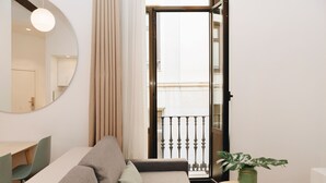 A modern living room with a sofa, a dining table, and a potted plant. - Apartamentos Wallace Valencia (Valencia)