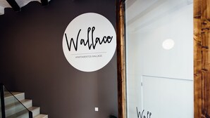 A staircase with a dark wall and a circular logo that reads "Wallace Apartamentos Wallace". - Apartamentos Wallace Valencia (Valencia)