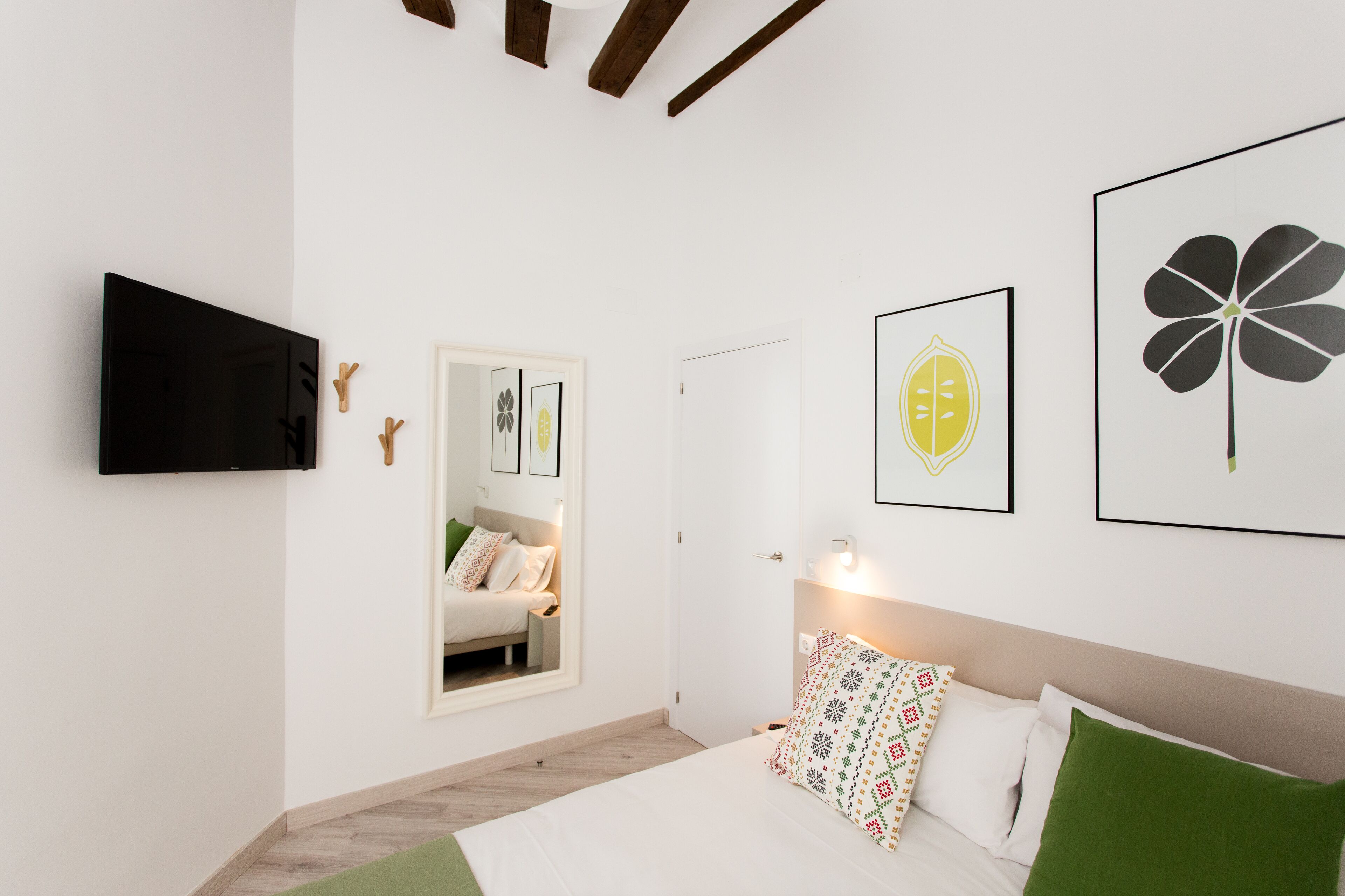 Een moderne slaapkamer met een bed, een televisie en kunstwerken aan de muur.