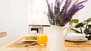 A breakfast setting with a croissant, orange juice, and a white pitcher on a wooden table. - Apartamentos Wallace Valencia (Valencia)