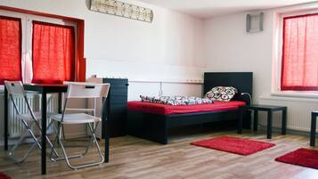 A small, modern bedroom with a bed, a desk, and two chairs.