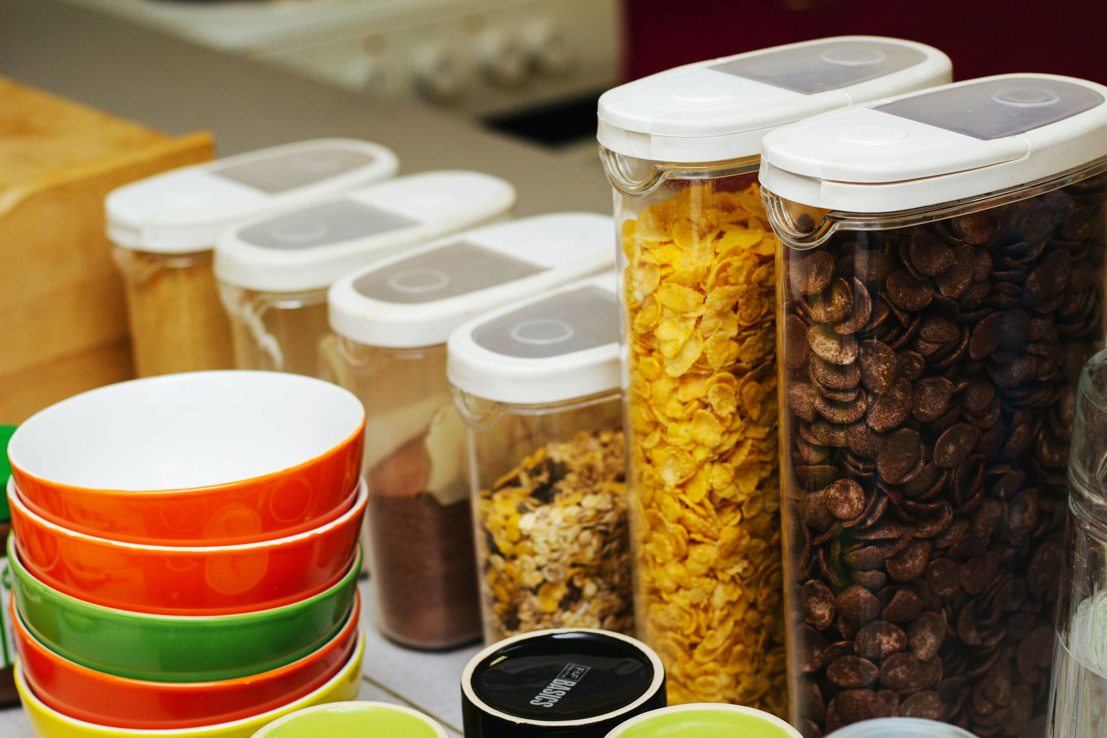 Diversos recipientes para alimentos con tapas, incluyendo frascos y cuencos, sobre una mesa.