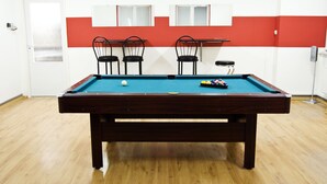 Una mesa de billar con cuatro sillas, una puerta blanca y una pared roja y blanca.