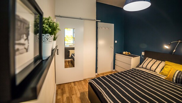 Un dormitorio con cama, mesita de noche, lámpara y armario.