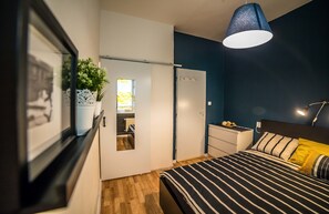 Un dormitorio con cama, mesita de noche, lámpara y armario.