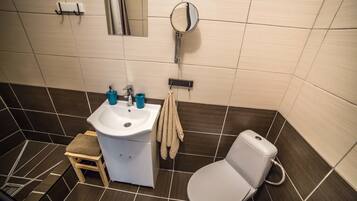 Une salle de bain avec un lavabo blanc, des toilettes et un miroir.