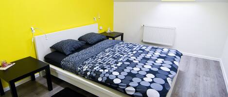 Un dormitorio moderno con una cama, una mesita de noche, una pequeña mesa y un tragaluz.