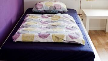 A bed with a patterned bedspread and pillows, a bedside table, and a lamp.