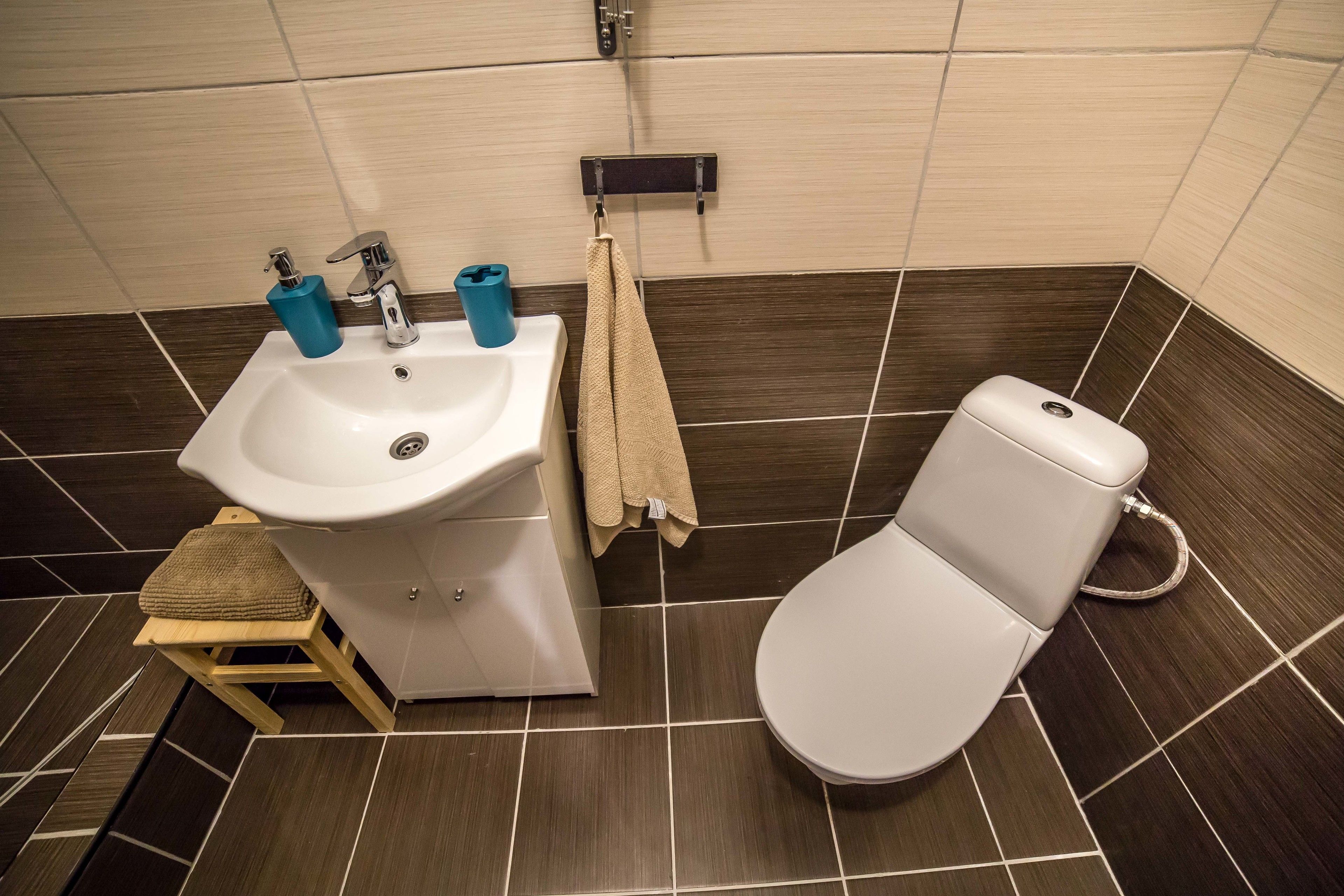 Ein Badezimmer mit Waschbecken, Toilette und einem kleinen Hocker.