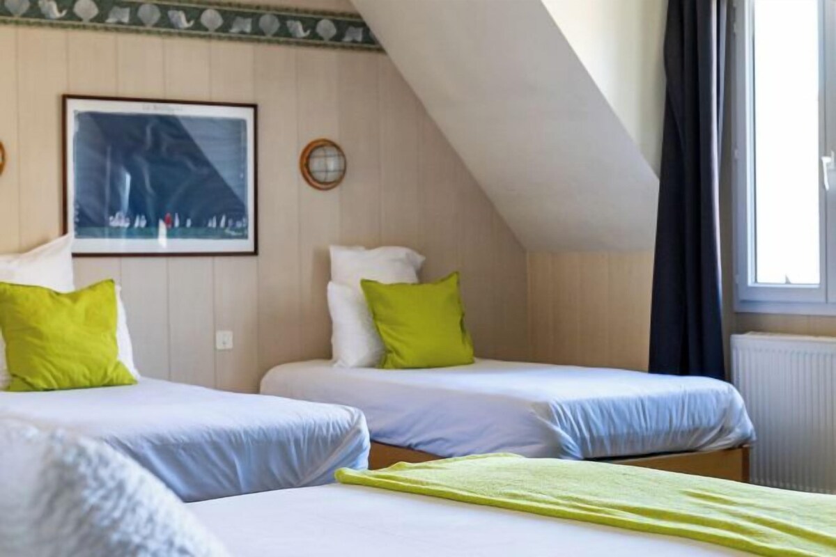 Una habitación con dos camas, un cuadro en la pared y una ventana con cortinas.
