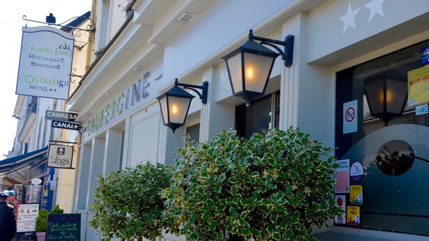 Ein Gebäude mit Schildern für 'L'Auberg Restaurant Brasserie' und 'L'Ostale Hotel'.