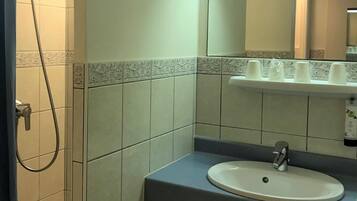 Un baño con ducha, lavabo y espejo.