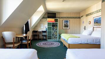 A room with two beds, a desk, chairs, a television, and a window.
