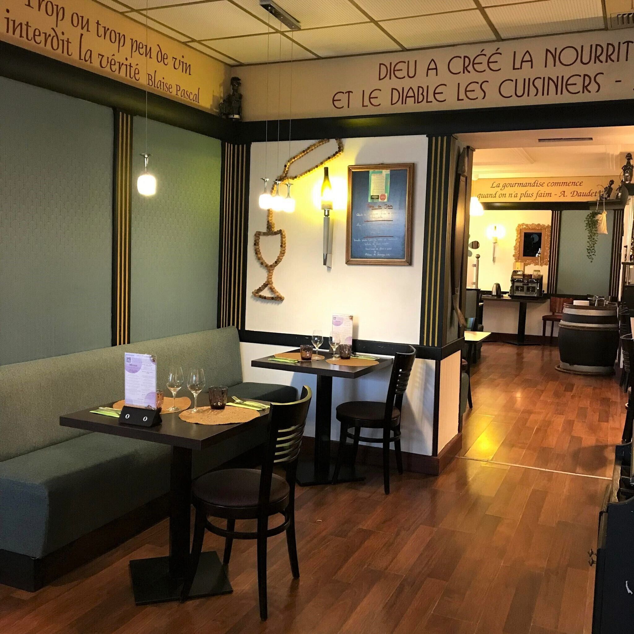 Interior de restaurante con cabinas y mesas, suelo de madera y adornos en las paredes, incluyendo un certificado enmarcado y una cita.