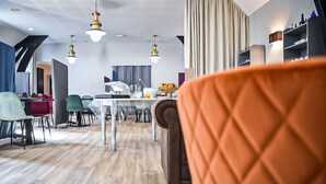 Ein modernes Wohnzimmer mit einem braunen Sessel, einem Essbereich mit Tisch und Stühlen und einer Küche im Hintergrund.