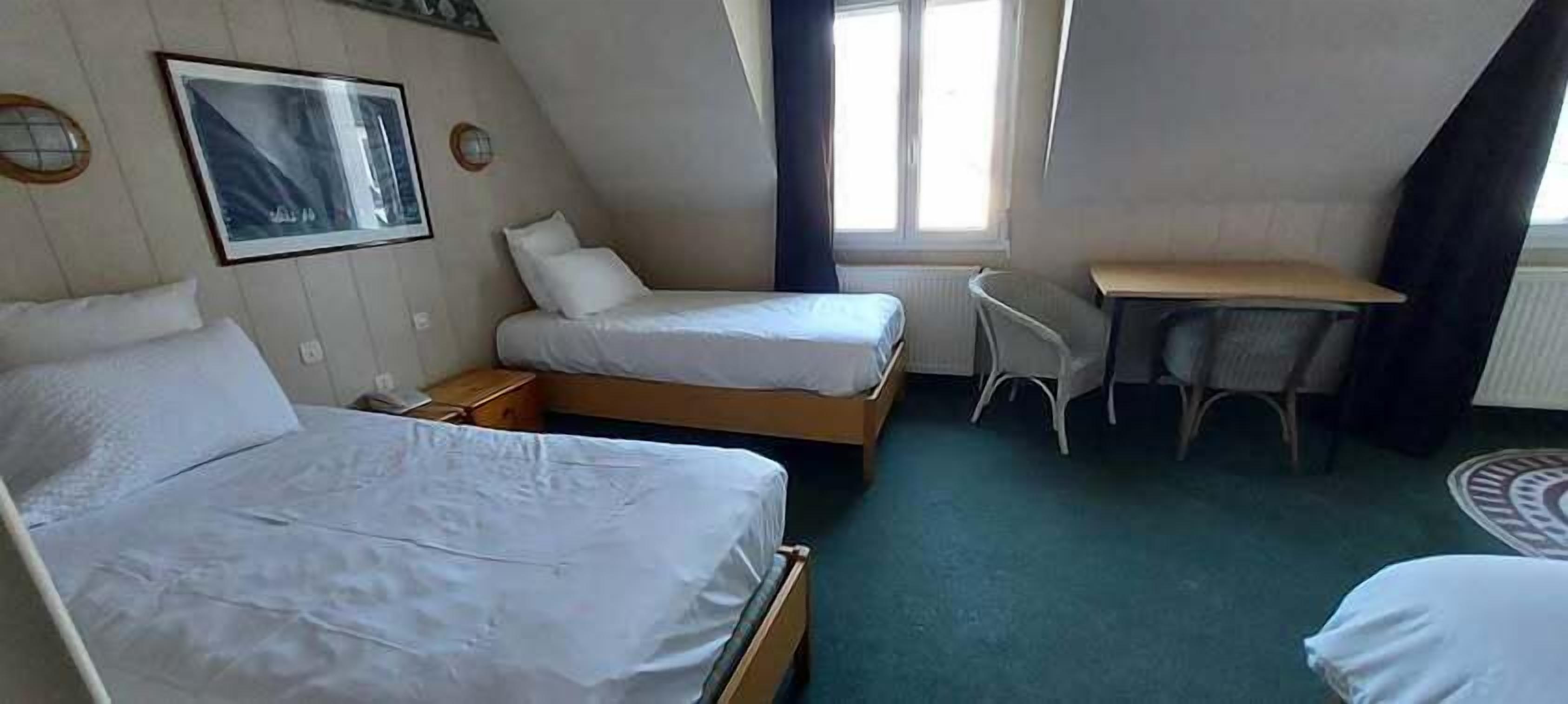 Een hotelkamer met twee bedden, een bureau en een stoel.