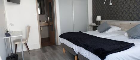 Un dormitorio moderno con cama, mesita de noche, lámpara y televisor montado en la pared.