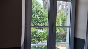 Ein Fenster mit Blick auf ein Gebäude mit aufwendiger Architektur und umliegender Bepflanzung.