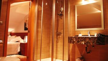 Un baño moderno con ducha de vidrio, tocador de madera y un inodoro a la vista.