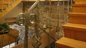 Un escalier en bois, avec des murs en pierre et une rampe en verre.