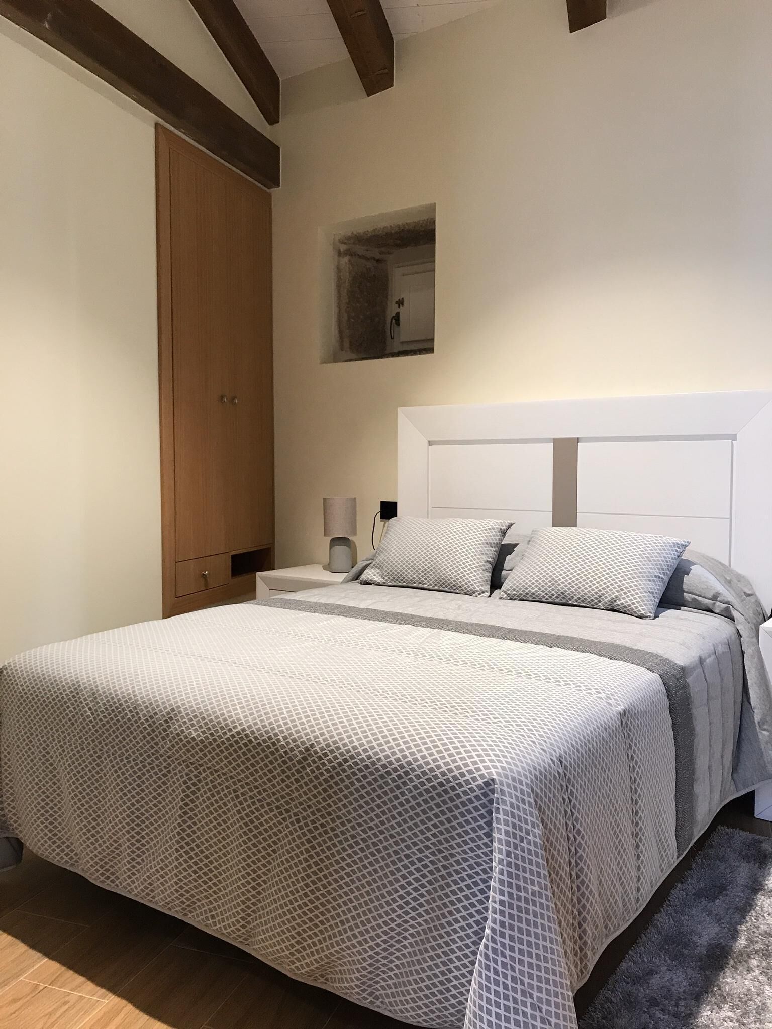 A bedroom with a large bed, wooden wardrobe, bedside tables, and a nightstand.