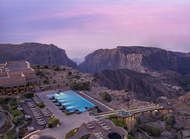 A resort with a swimming pool, outdoor seating, and a view of a canyon.