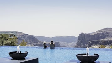Una piscina al aire libre, sombrillas, sillones reclinables de piscina