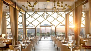 Ristorante con vista sulle montagne, tavoli apparecchiati per la cena e lampade a sospensione.